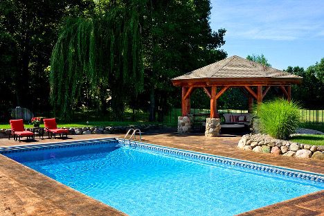 Log gazebo behind a swimming pool