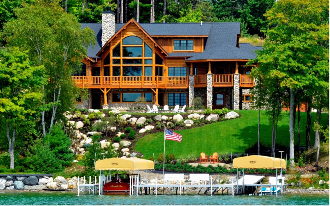 Log home overlooking a lake with a dock and boats.