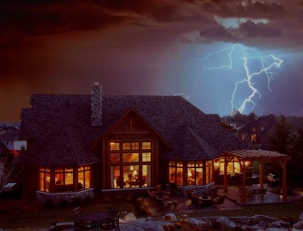 Log home at night with lightening in the sky