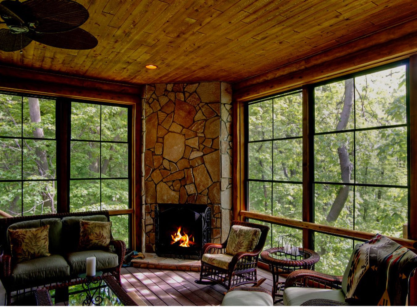 Interior of a log home with a fireplace and large windows looking out a forest